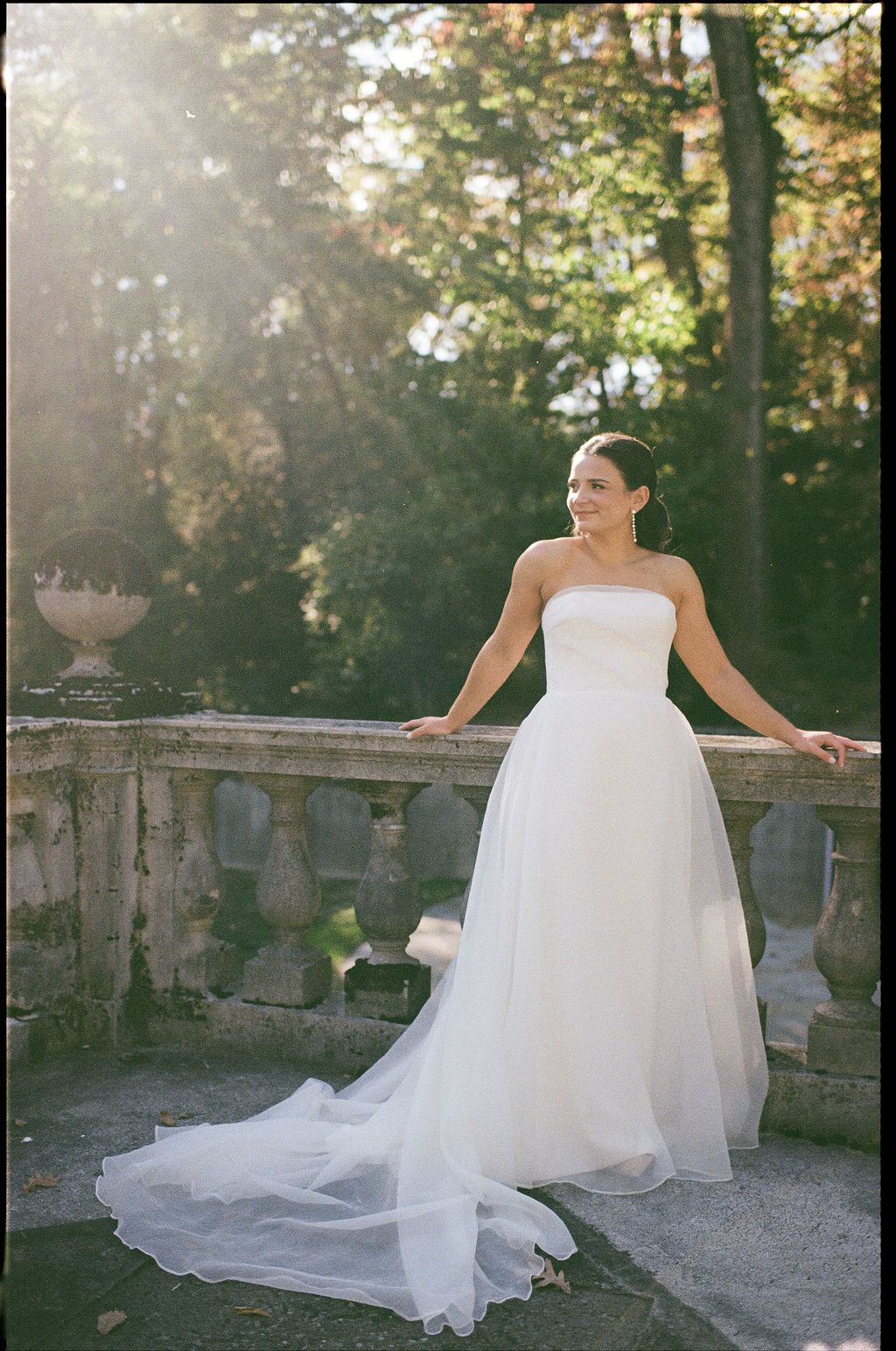 A flowing white wedding dress billows in the breeze on stone steps during sunset at Strong Mansion on Sugarloaf Mountain