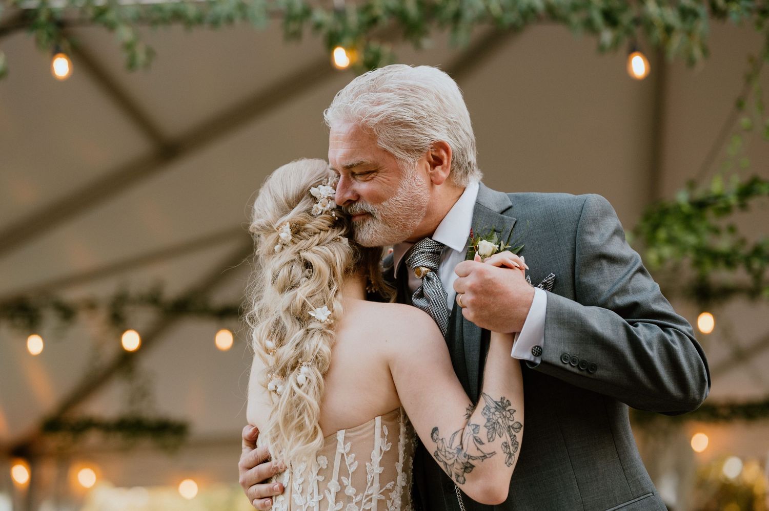 Emotional dance moment between two people during wedding reception under string lights.