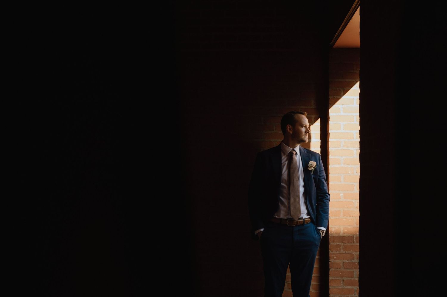 Dramatic lighting captures a suited figure standing in a doorway.