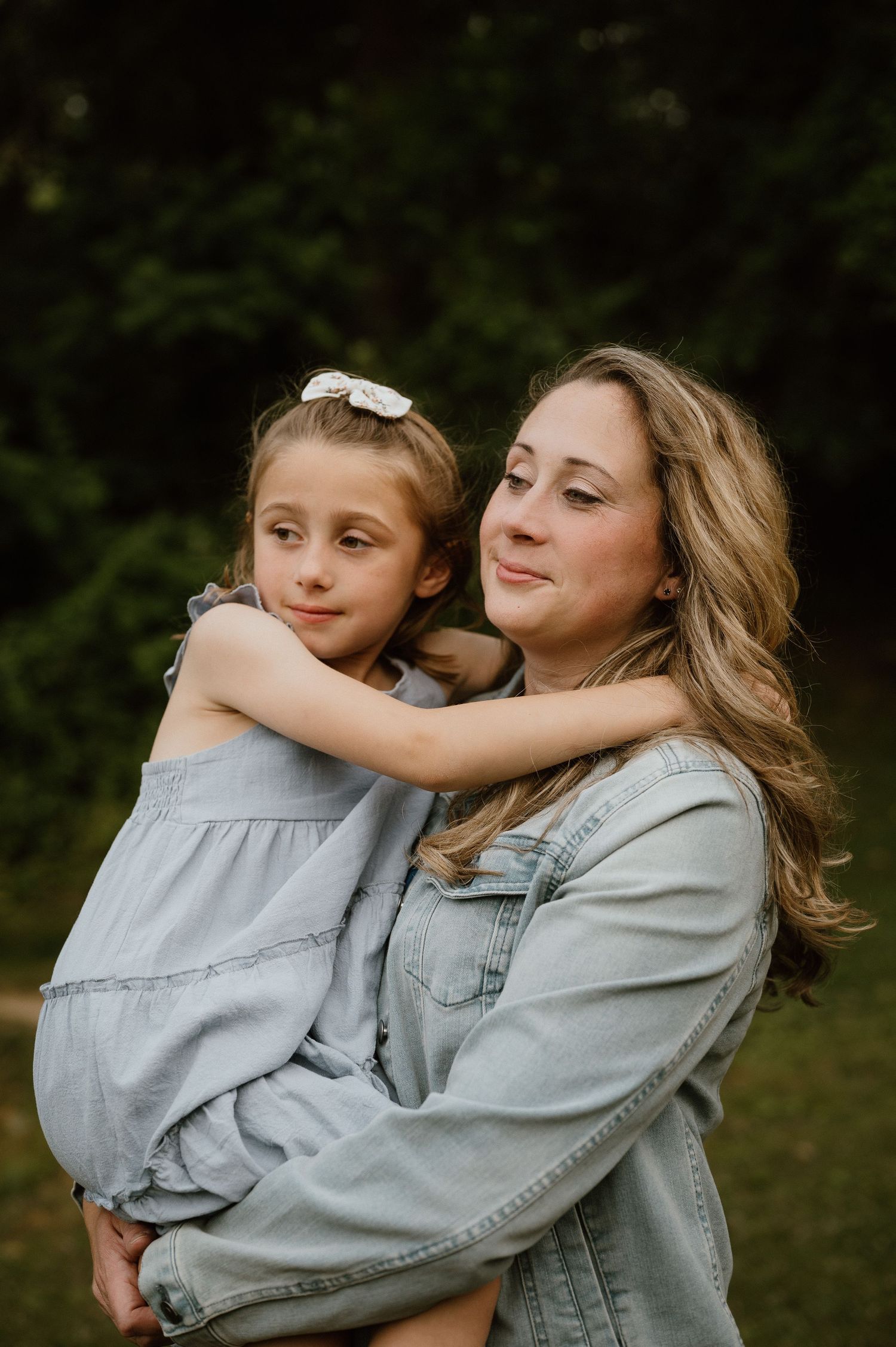 Tender moment captured between parent and child in casual denim outdoors.