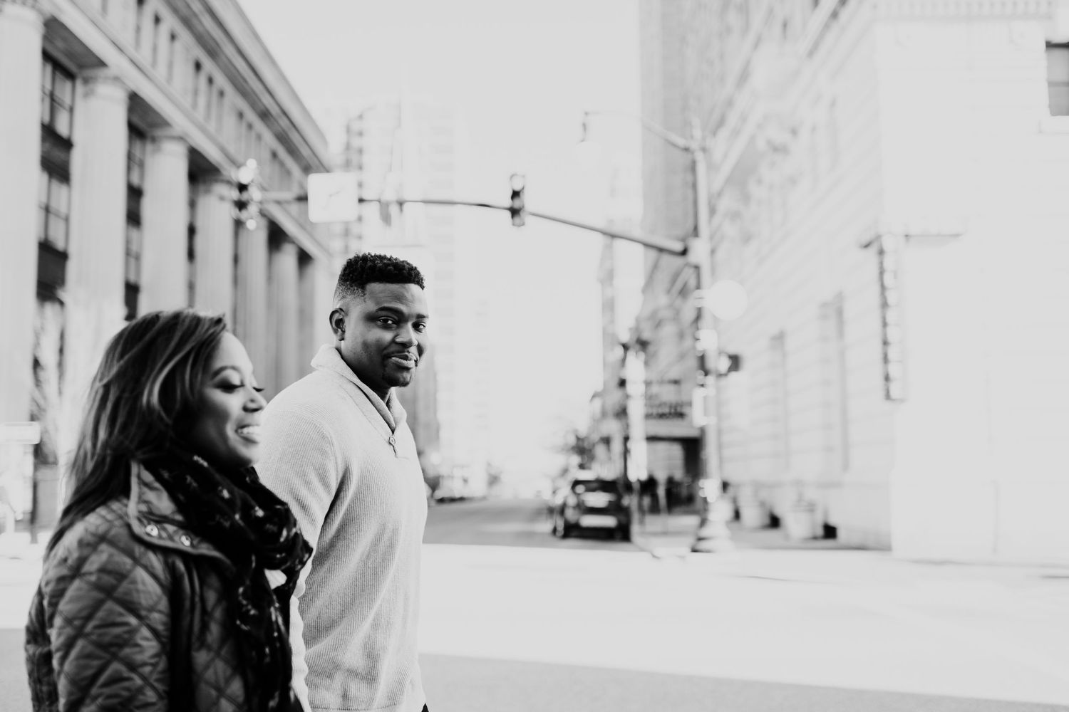 Black and white urban portrait of couple walking along city street.