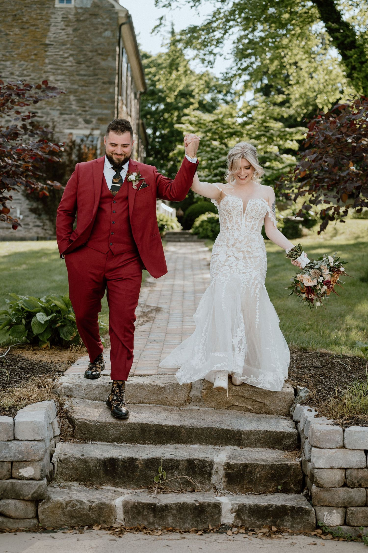 A couple celebrating on stone steps in formal wedding attire.