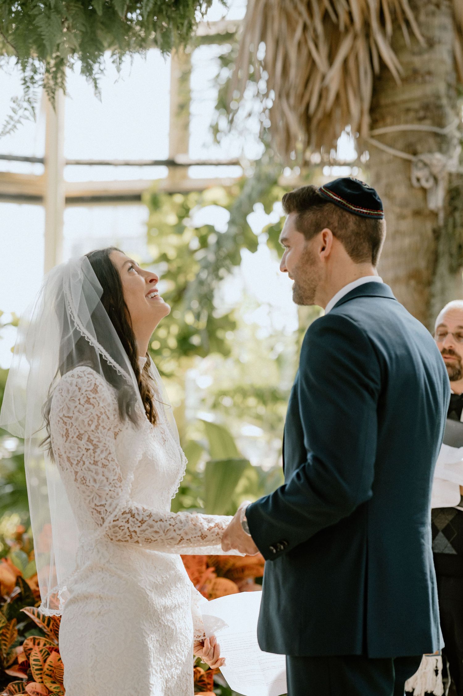 Couple exchanges vows during intimate greenhouse wedding ceremony.
