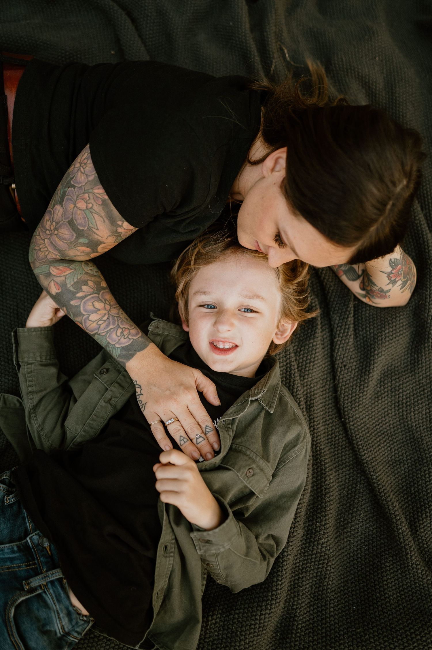 A playful and joyful moment shared on a cozy blanket outdoors with visible tattoo art.