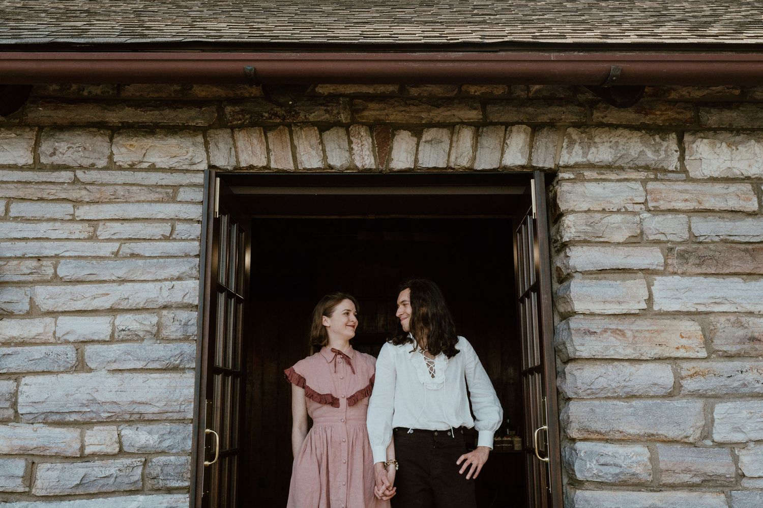 Two people posing together in a rustic stone doorway entrance.