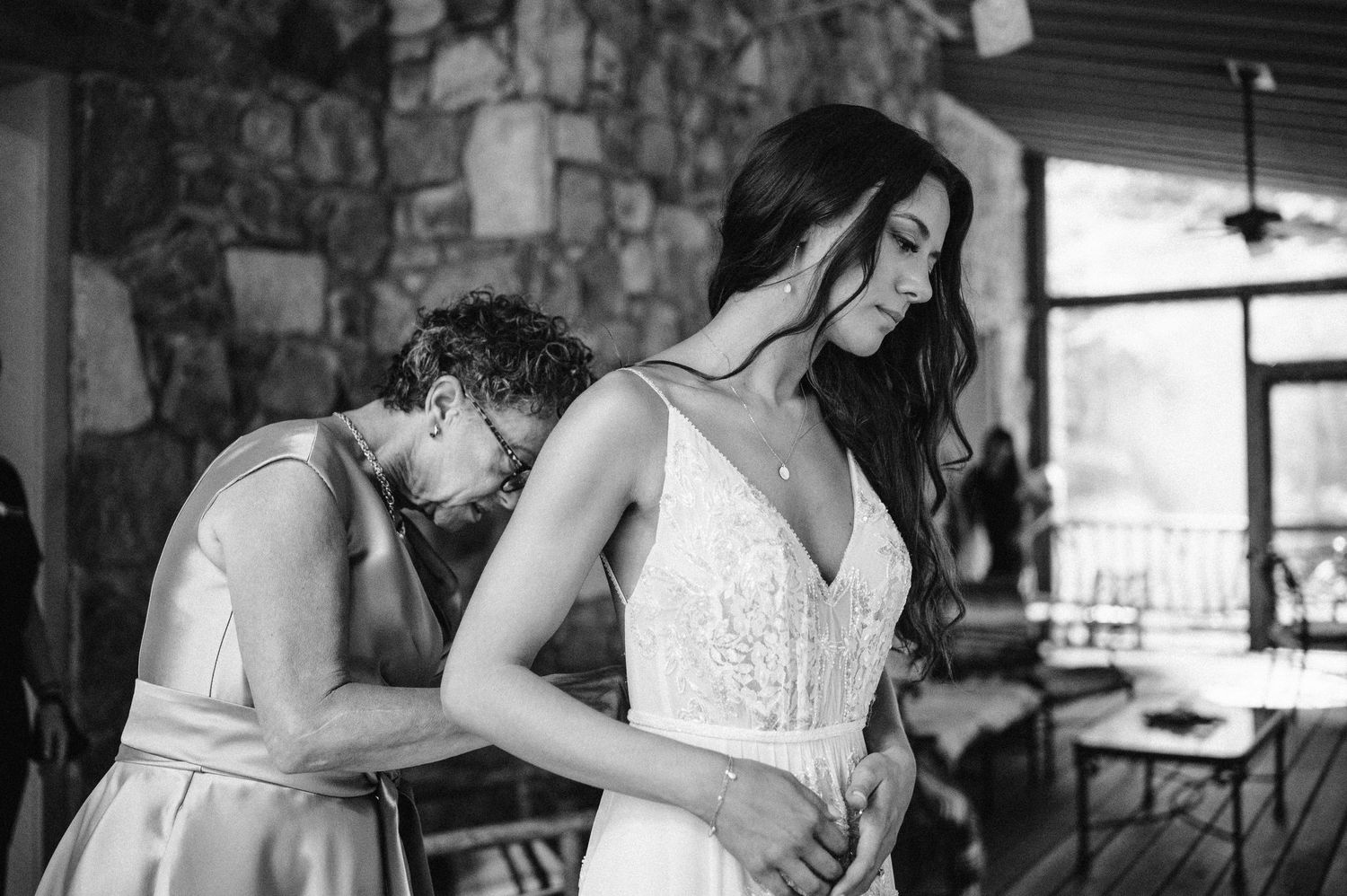 bride putting on her wedding dress with mother