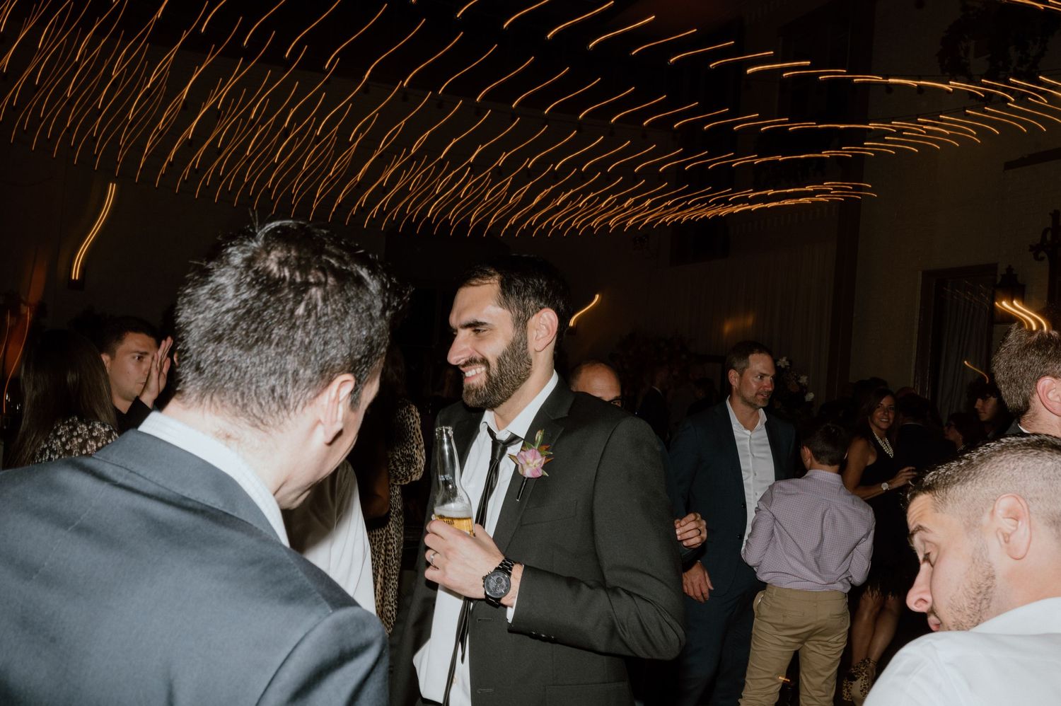 Guests engaged in conversation at an evening indoor event with atmospheric lighting.