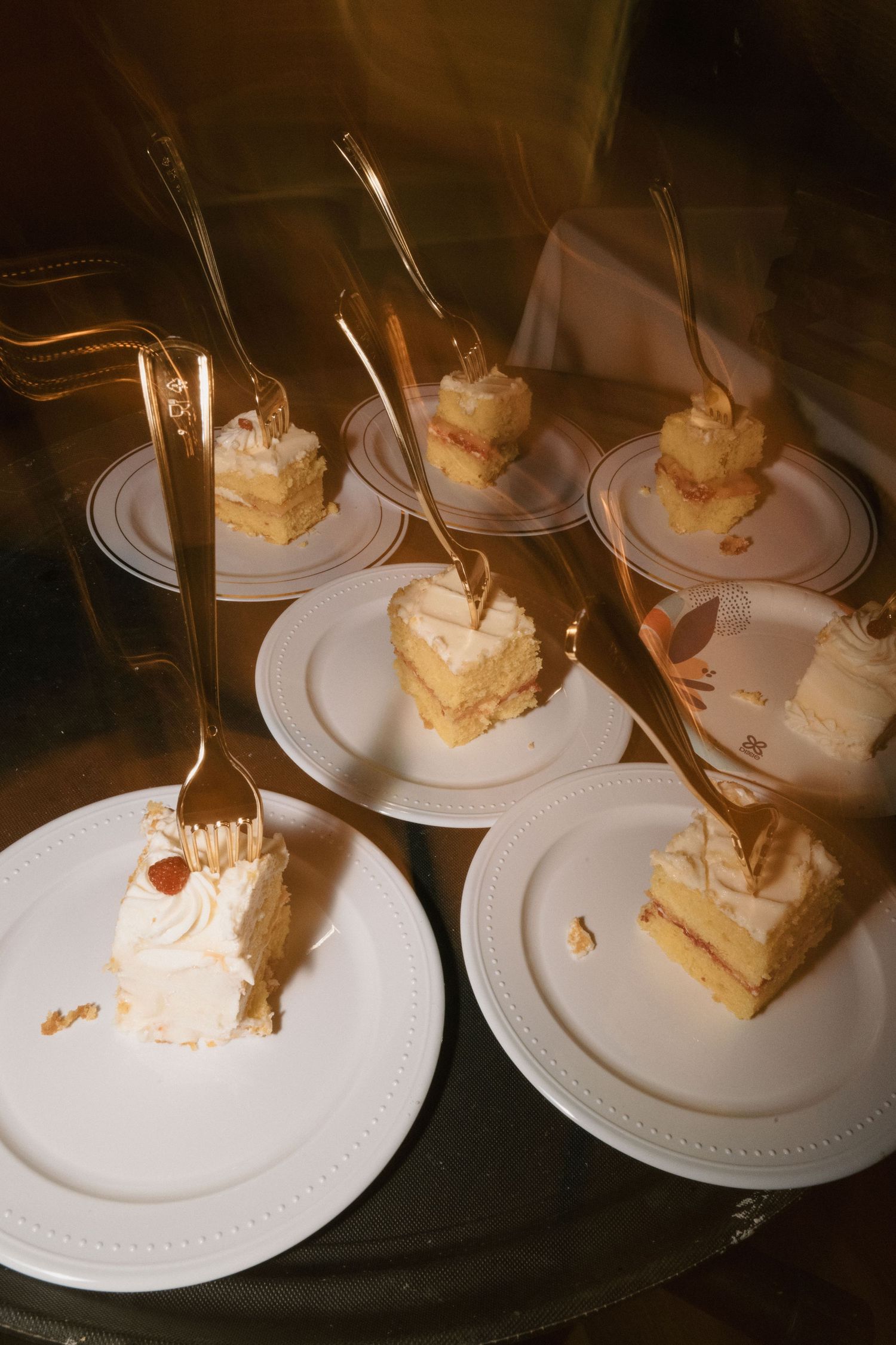 Elegant white wedding cake slices served on individual plates with decorative forks.
