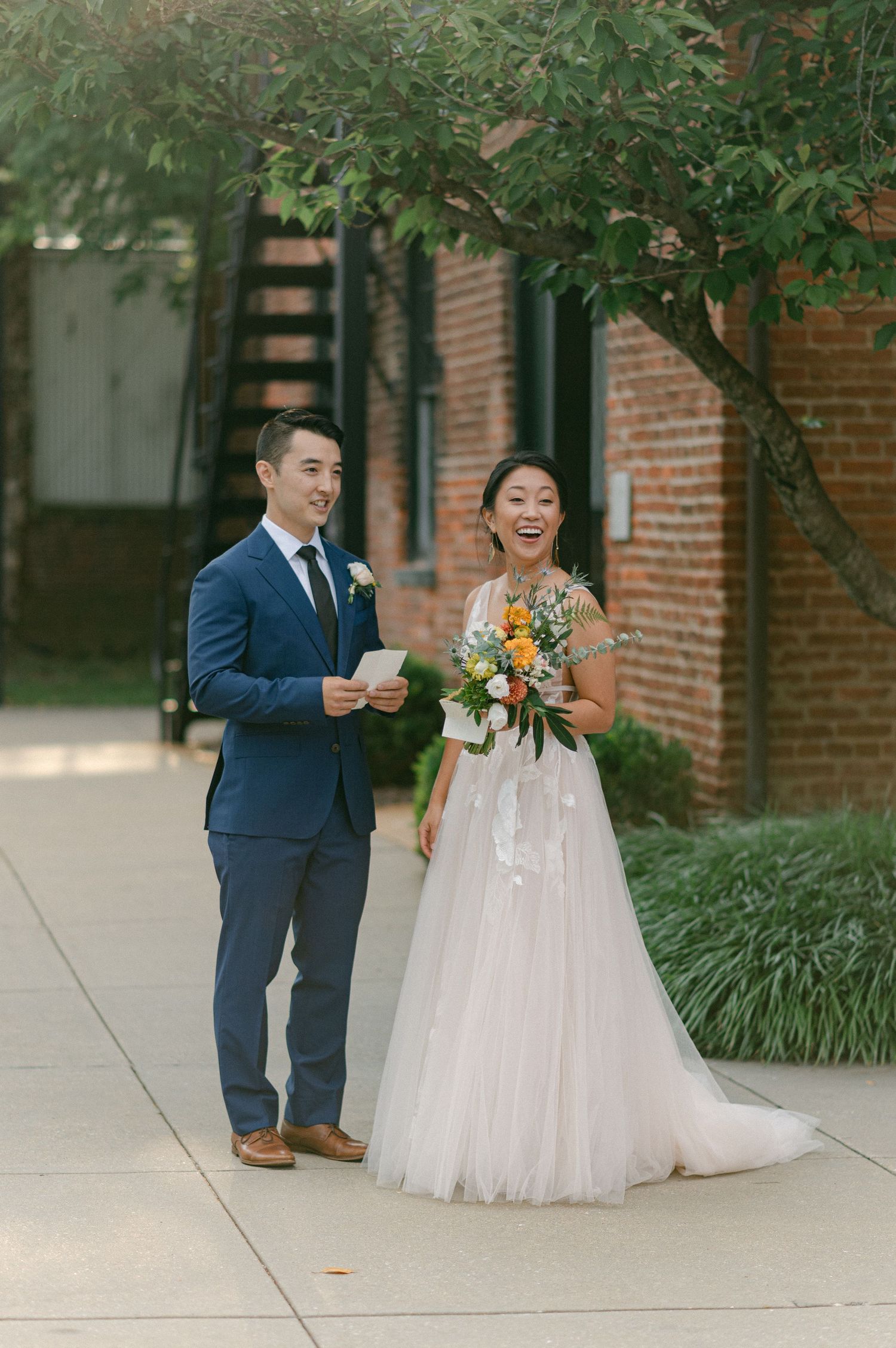 bride and groom smile in backlit sunny photo outside of brick building at the mt washington mill dye house