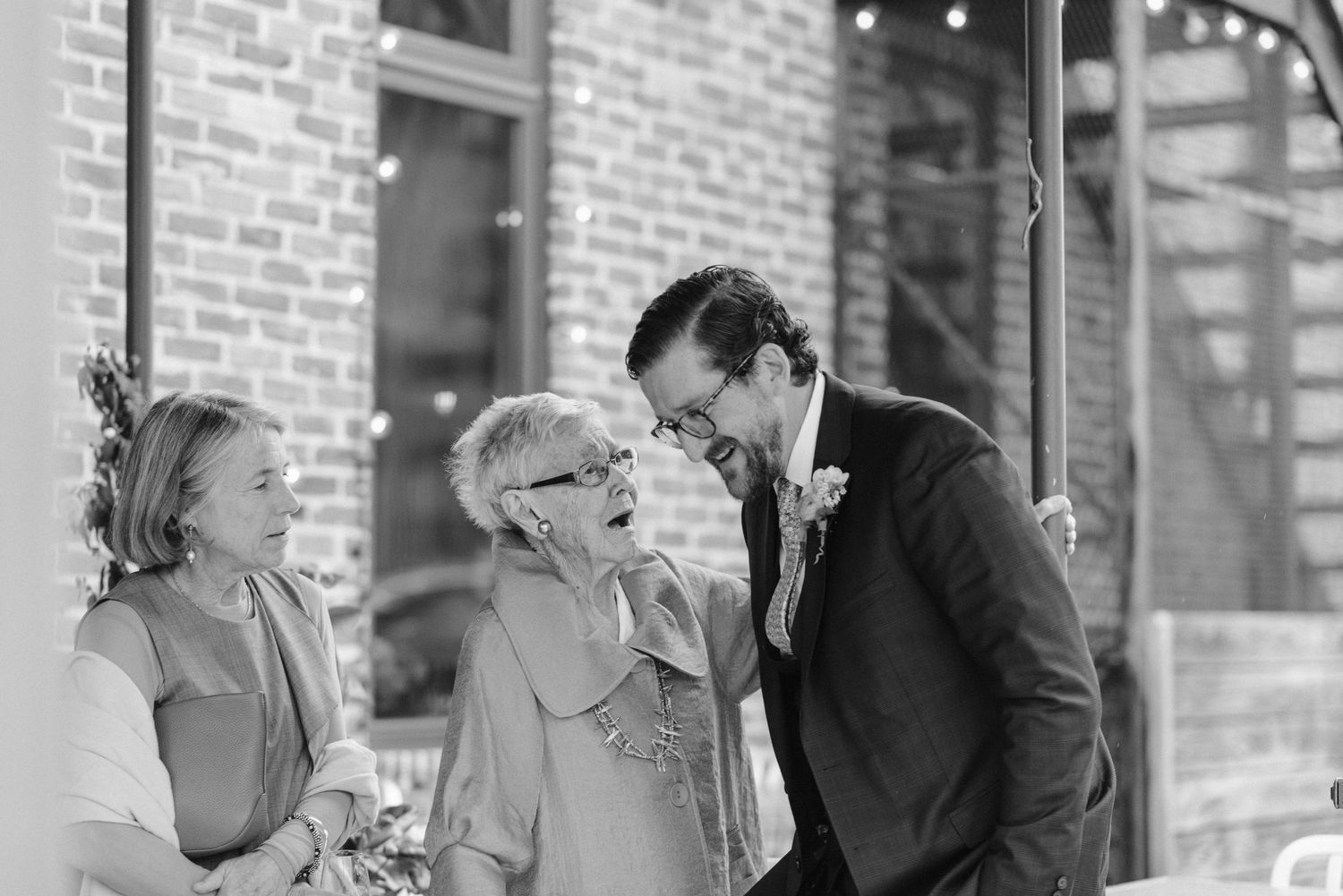 A candid moment shared between celebration attendees outside a brick venue.