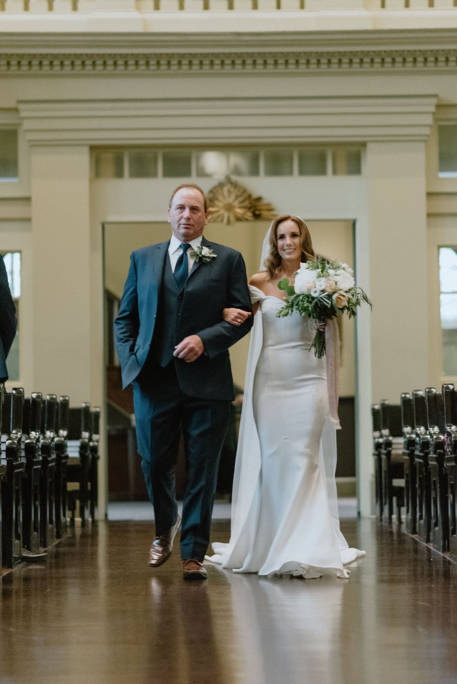 Elegant wedding procession in a grand church with classical architectural details.