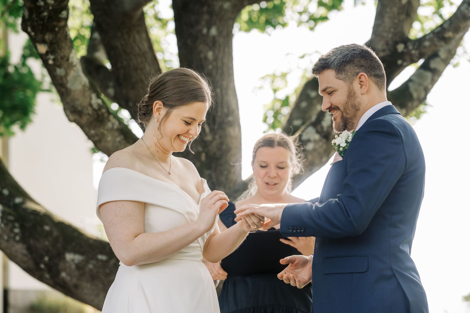 Couple sharing first kiss as newlyweds under a majestic tree during outdoor ceremony.