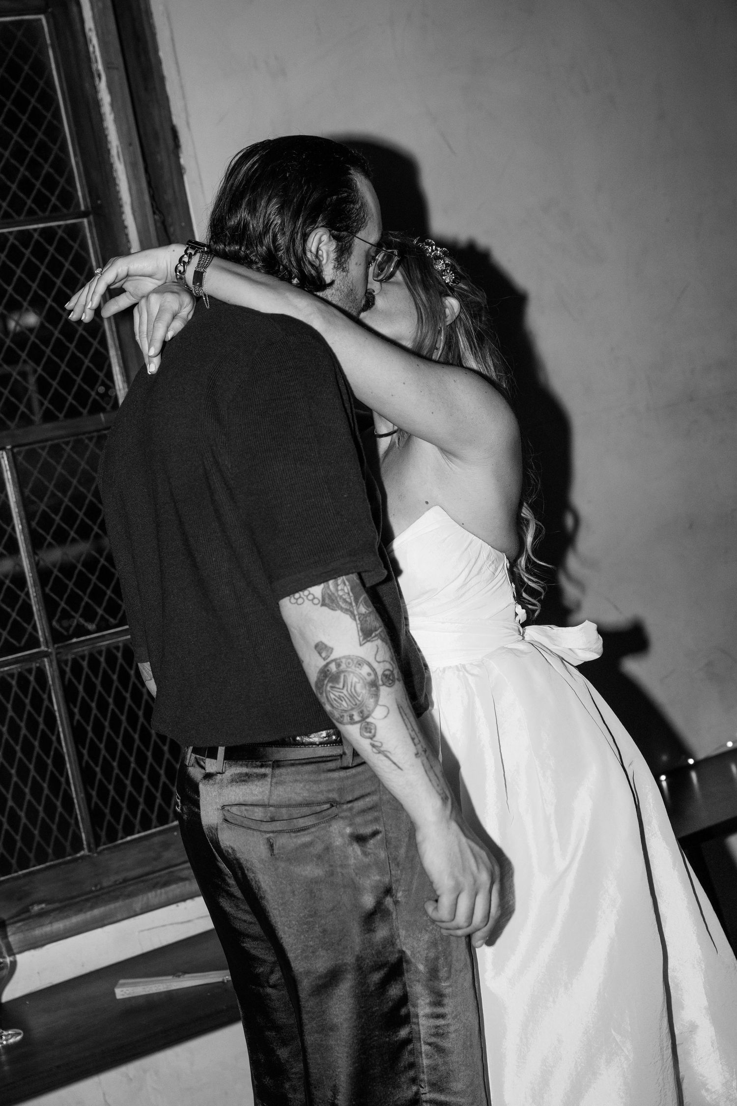 Black and white photo of intimate wedding dance between couple, bride in white dress and groom with visible tattoo at Fadensonnen