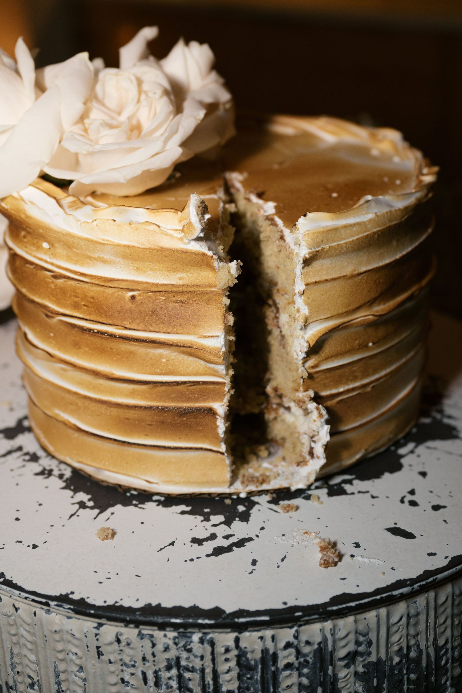 A stack of golden pancakes with a piece cut out sits on a glass cake stand decorated with a white rose.
