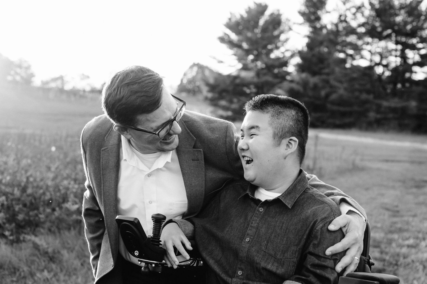 Black and white candid photo showing shared laughter between two people outdoors.