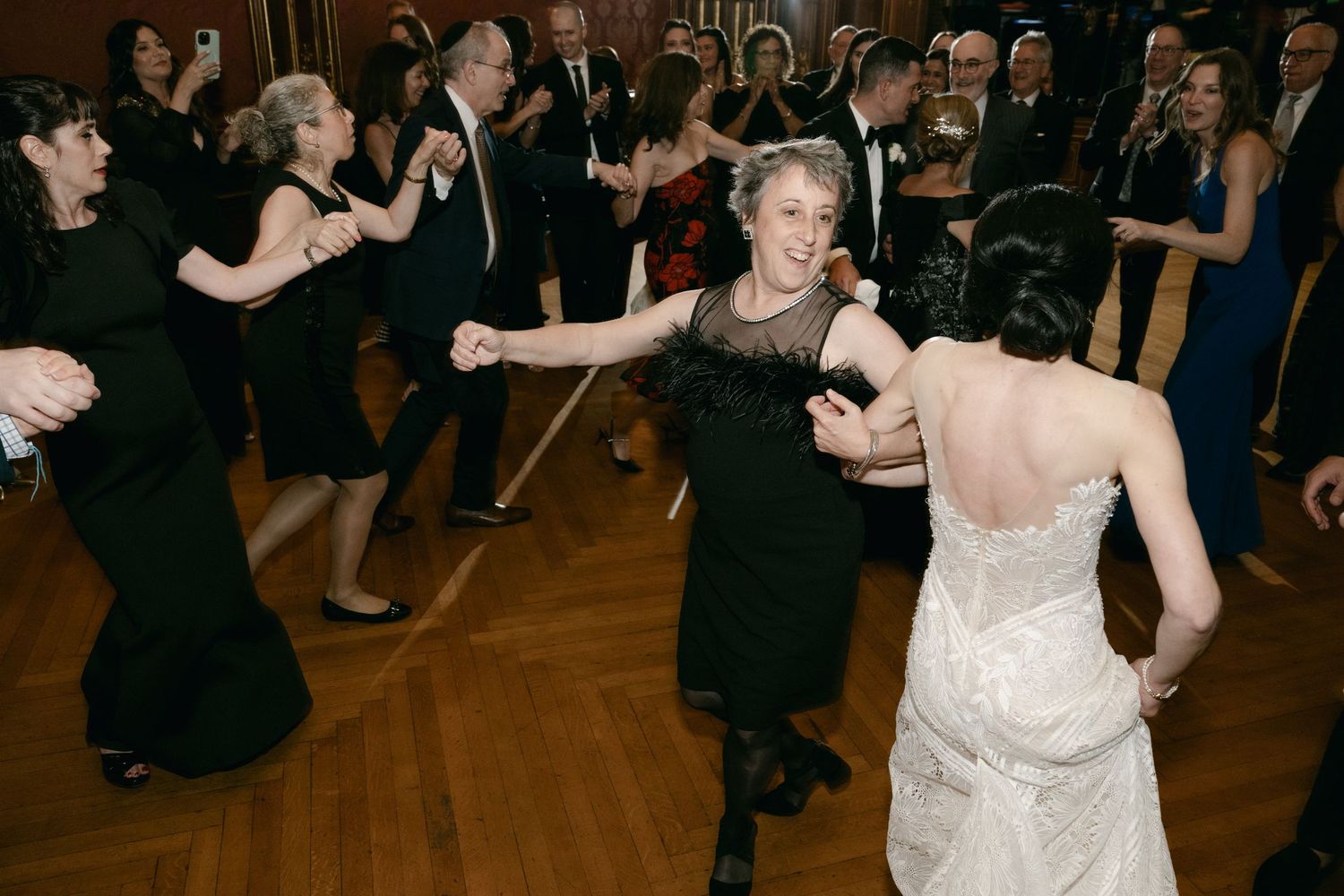 Wedding reception dance floor filled with guests celebrating in a warmly lit ballroom.