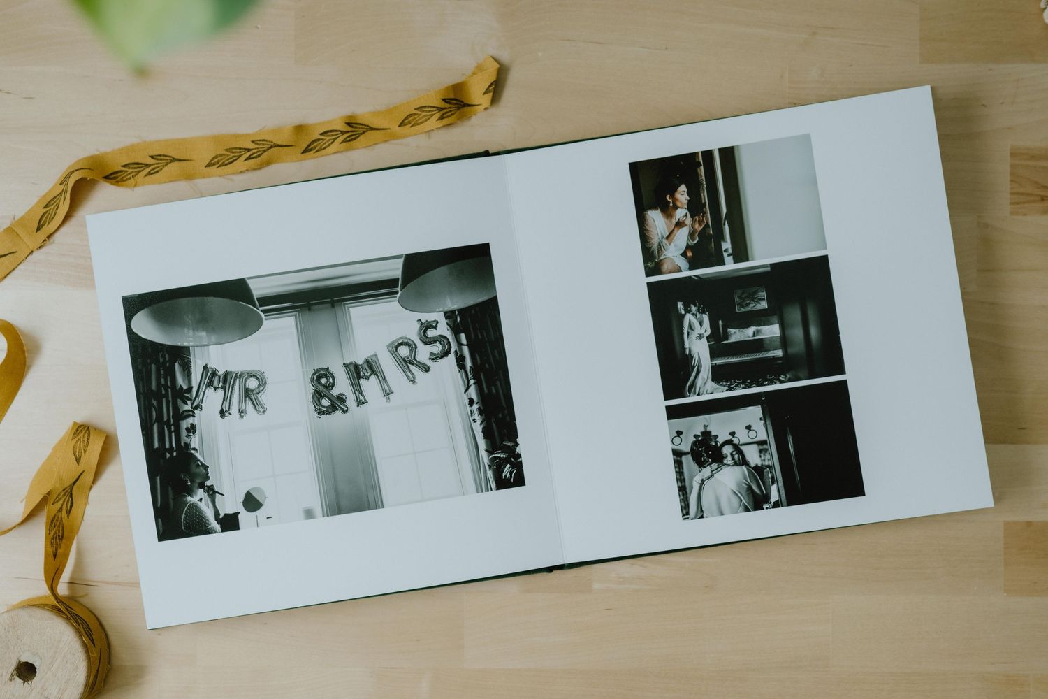 Row of black and white photo prints laid out on wooden surface.