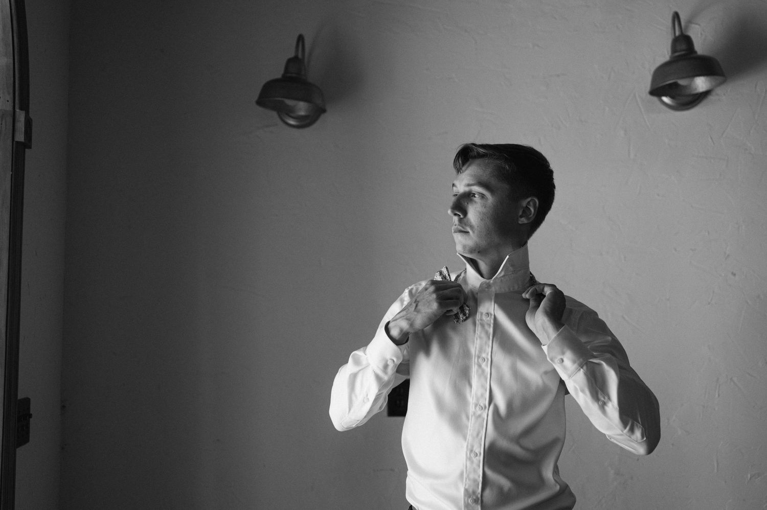 Black and white sequence of someone adjusting formal attire in preparation.