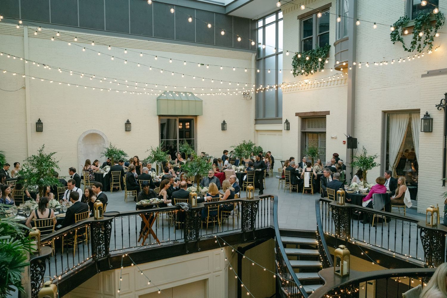 An elegant reception venue with string lights, balconies and guests seated at round tables at a Baltimore engineers club wedding