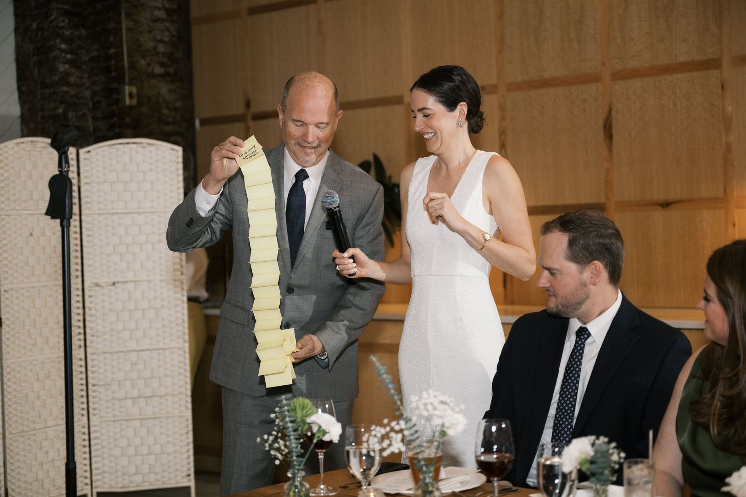 Wedding couple and guests raising glasses in a toast during an elegant reception dinner.