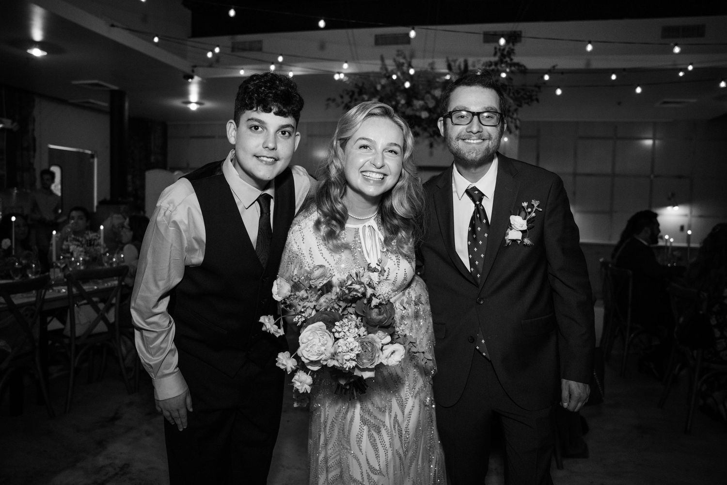 Black and white photo of wedding guests posing together at an indoor reception.