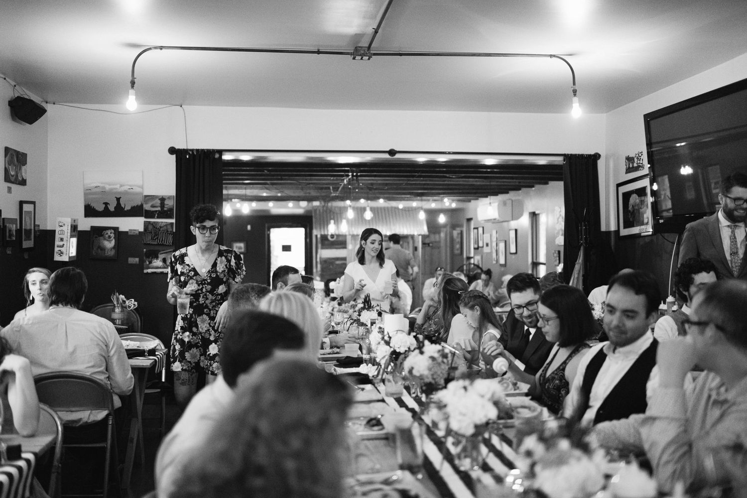Black and white photo of a crowded wedding reception at a restaurant bar.