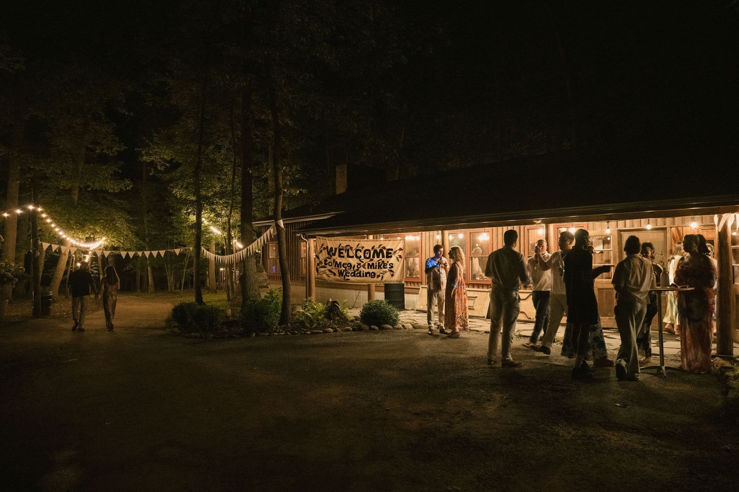 Outdoor evening event venue with string lights and tent structure illuminated against dark sky.