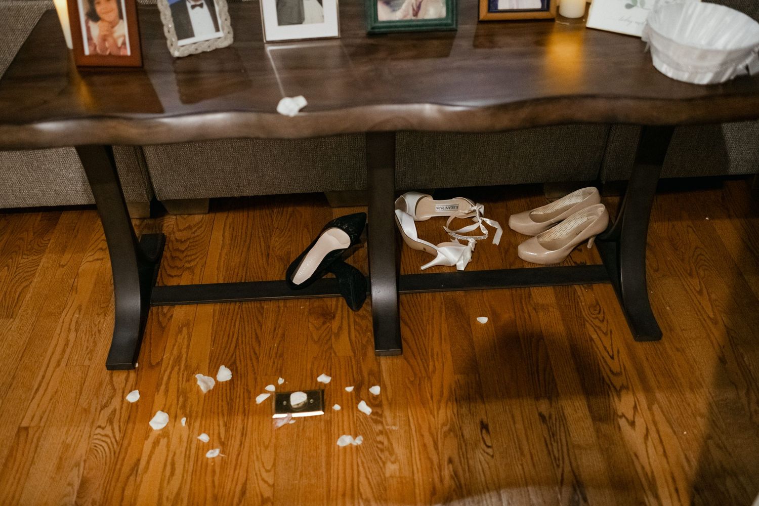 Wedding detail shot of wooden bench with scattered petals and shoes underneath.
