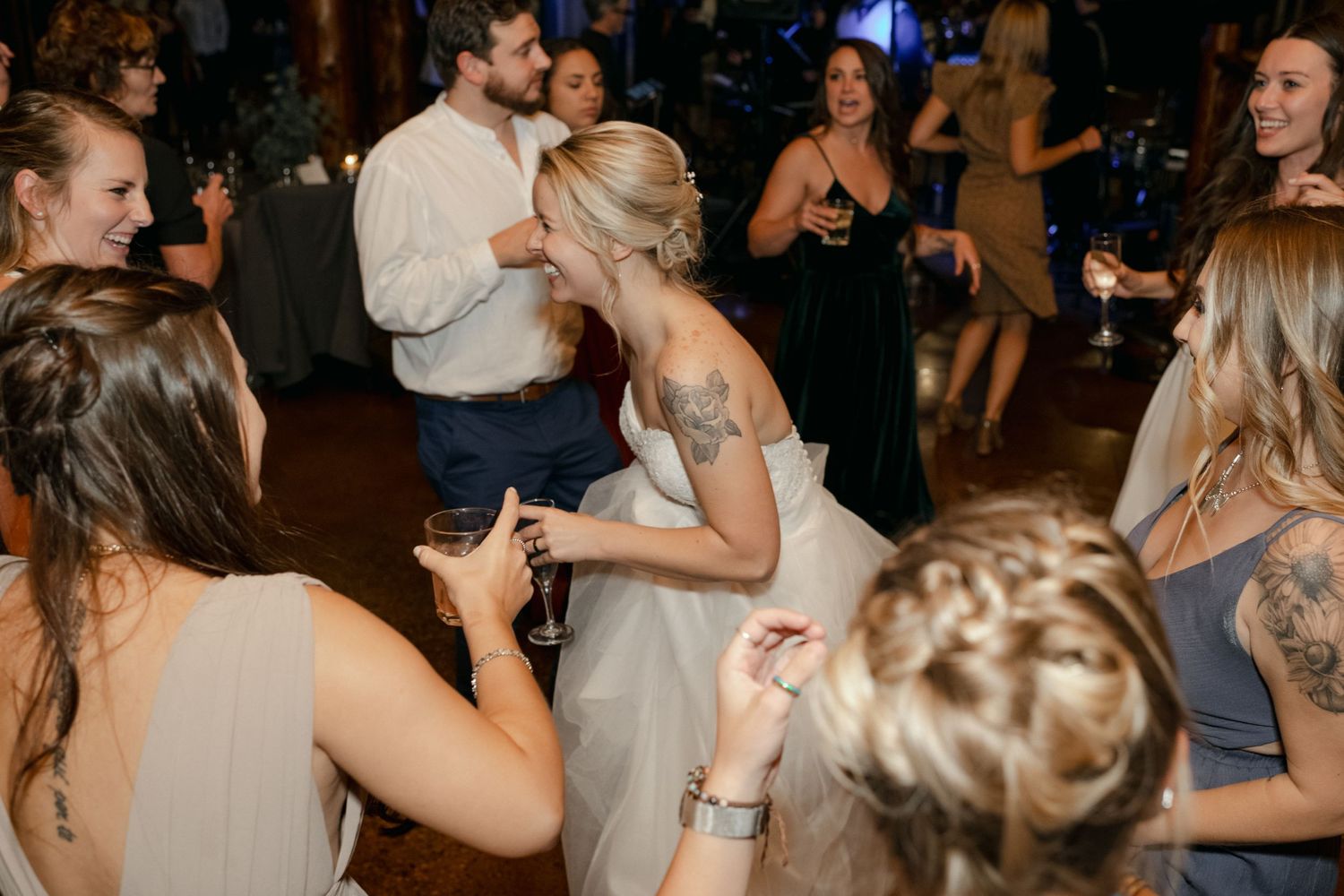 Wedding celebration on dance floor with guests dancing and taking photos.
