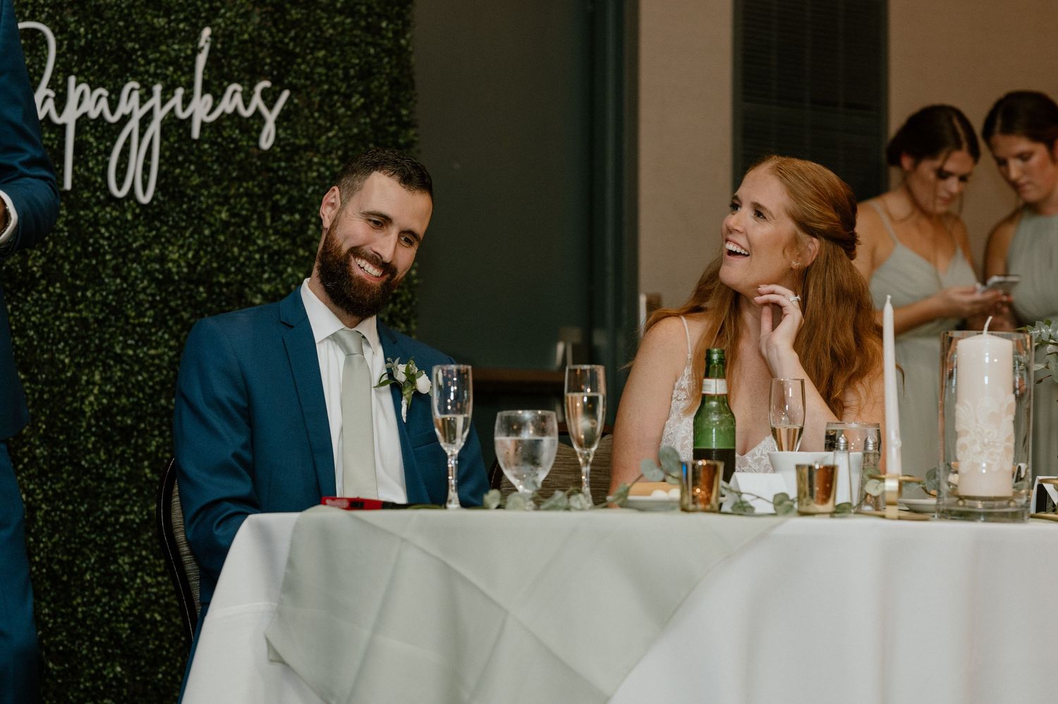 Newlyweds seated at their reception table share a candid moment together.