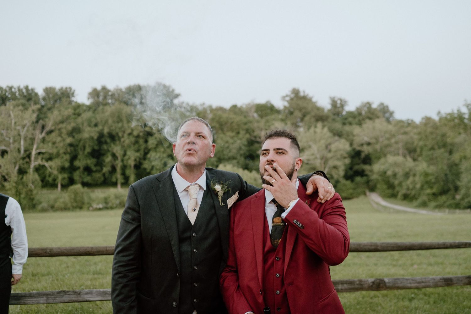 Two wedding guests sharing an emotional moment outdoors near a wooden fence.
