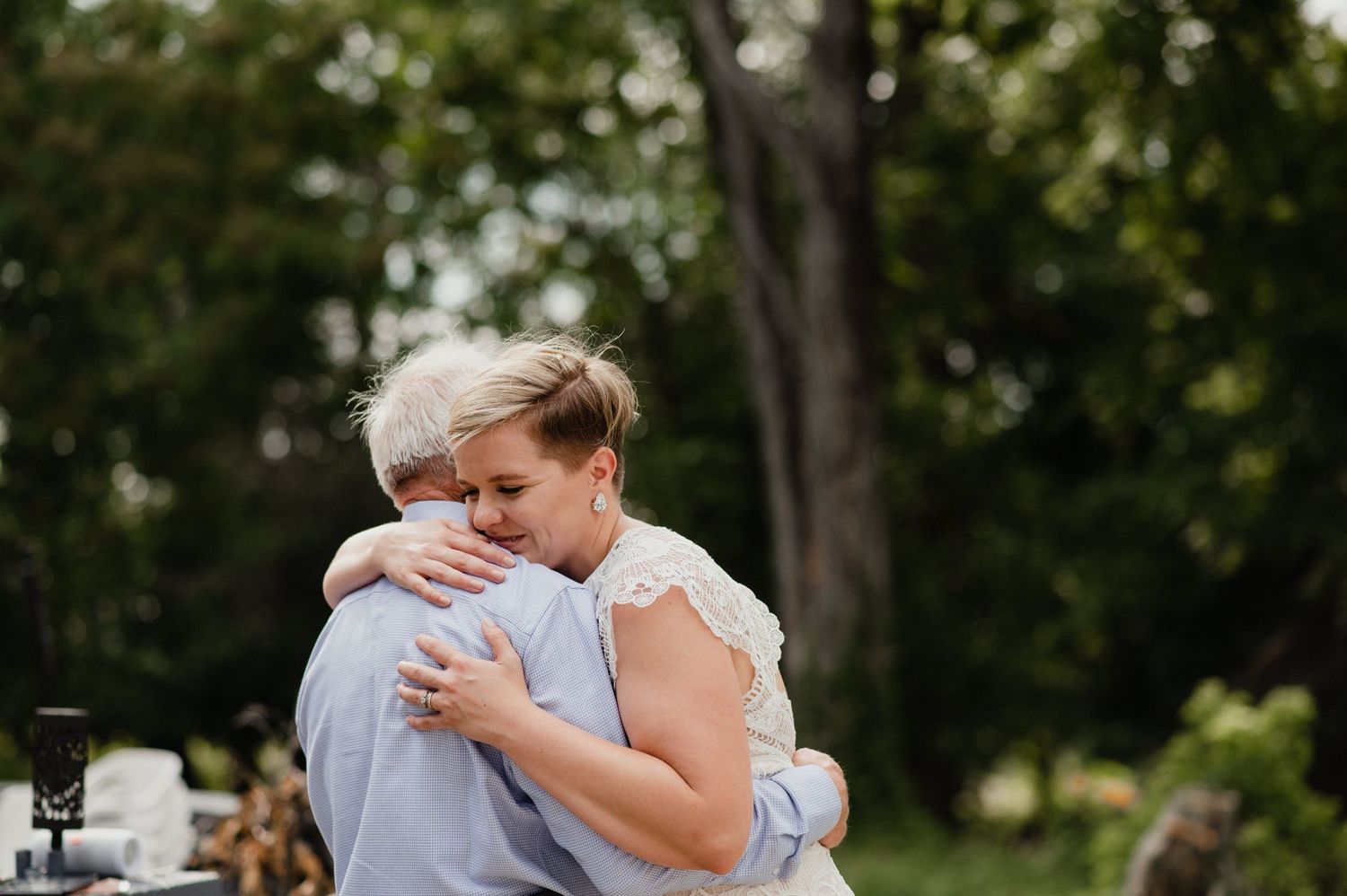 Tender embrace between newlyweds in a sunlit garden setting.