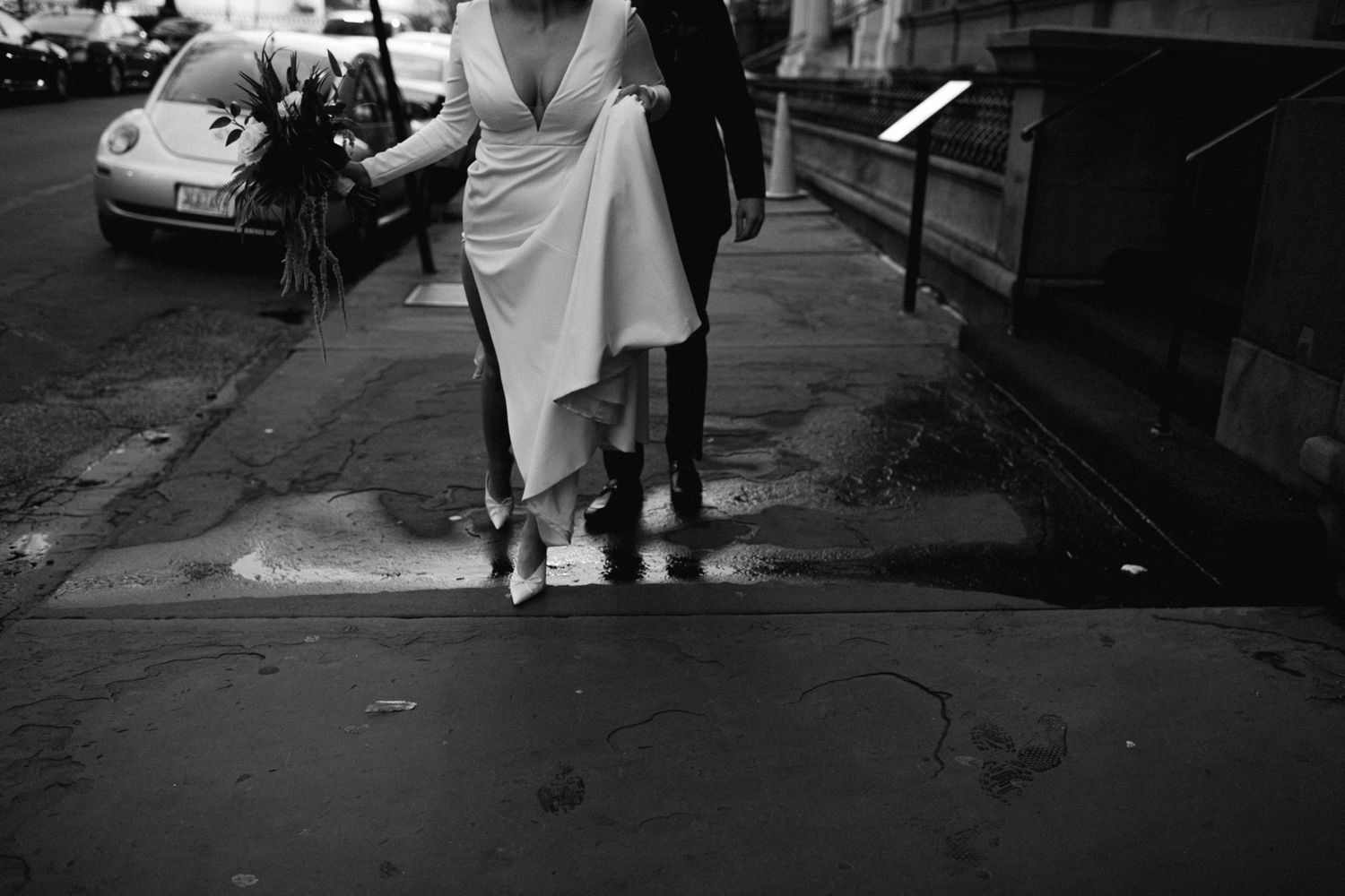 Black and white photograph of wedding couple's feet on city sidewalk.