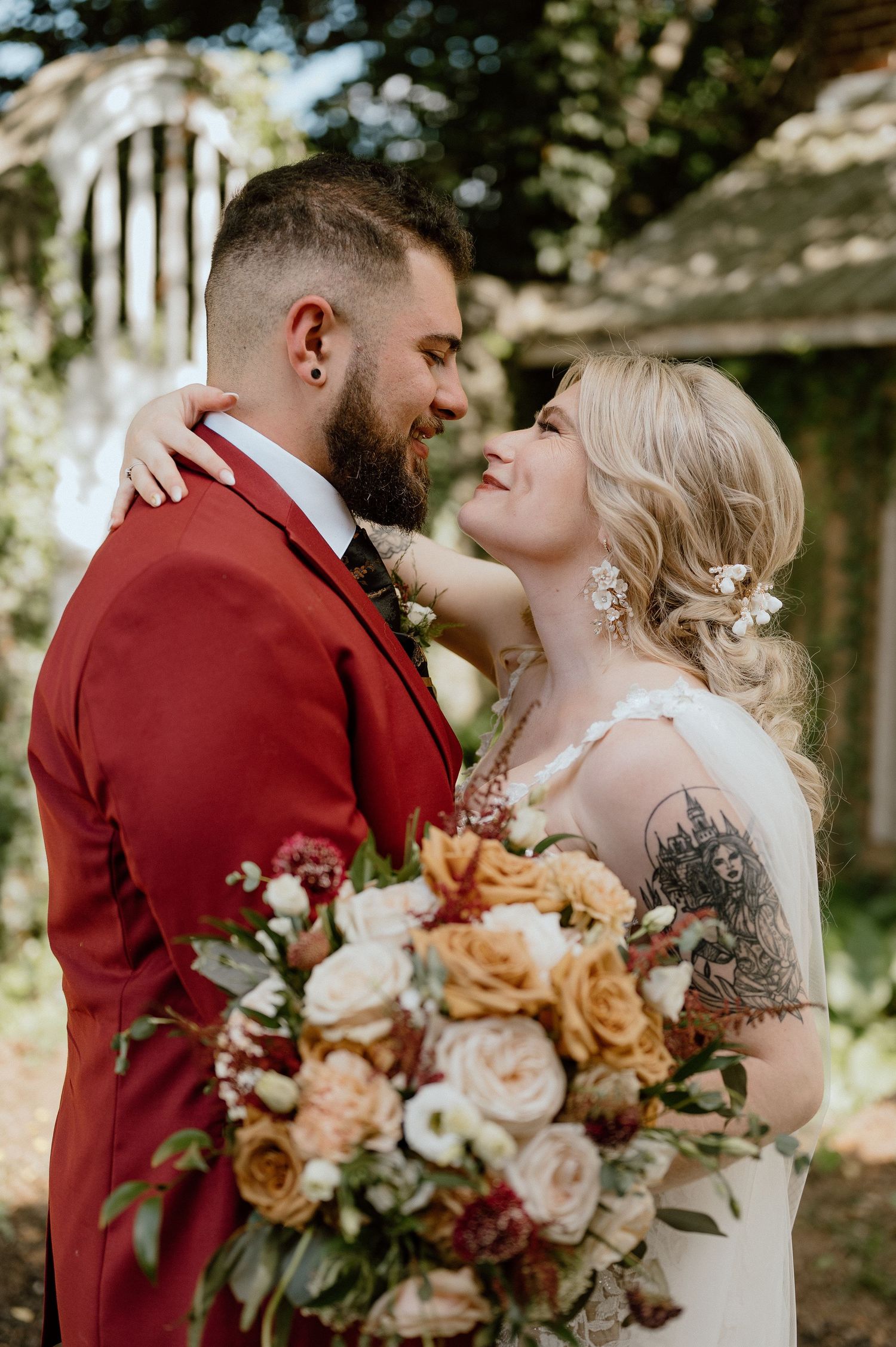 A tender wedding moment captured with peach and burgundy florals in an outdoor garden setting.