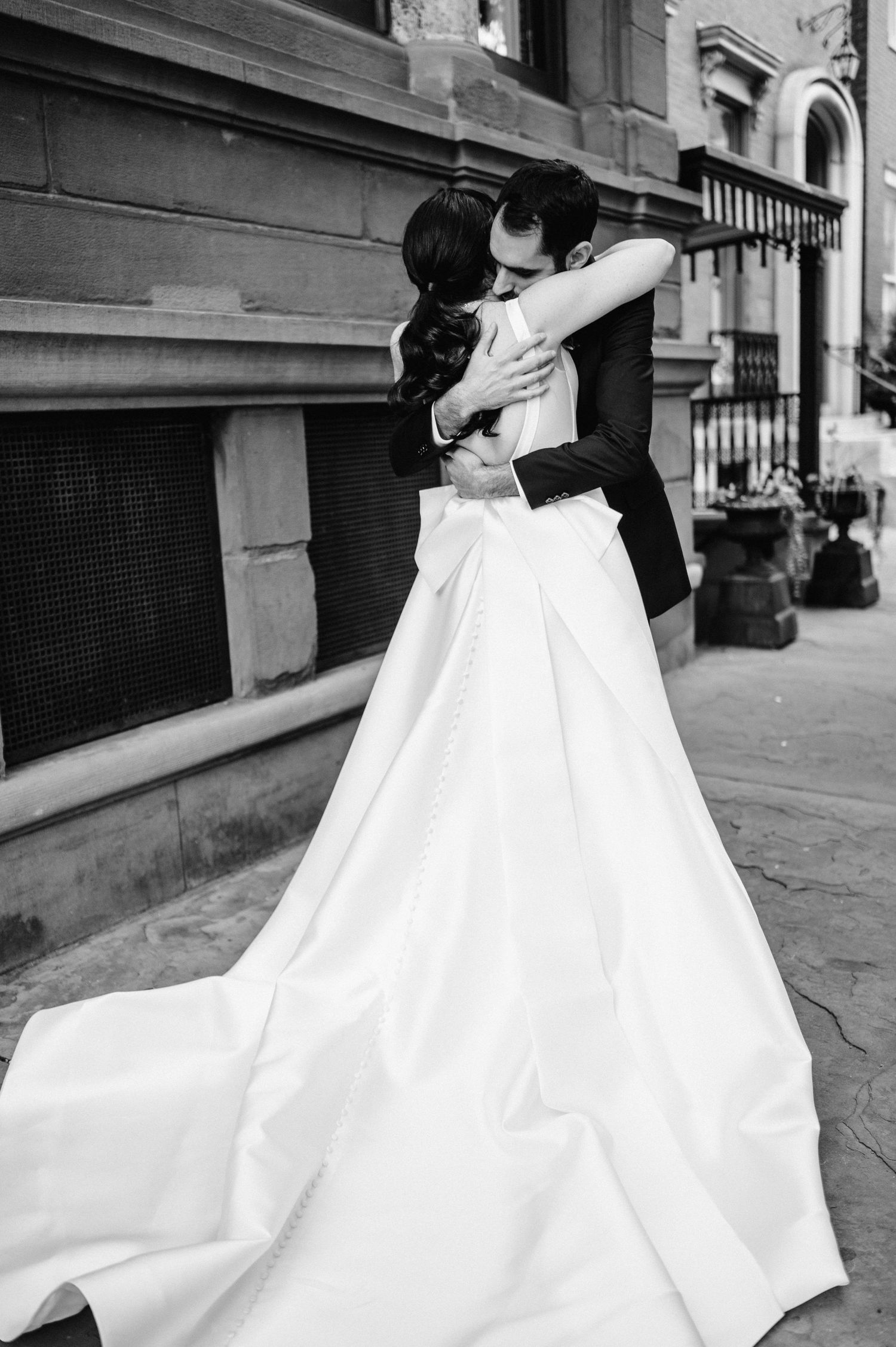 A romantic black and white wedding photo of a couple embracing, with the bride wearing a flowing white gown.