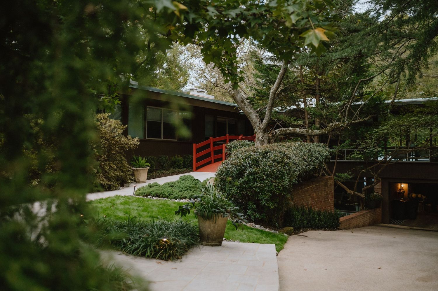 Japanese garden path with red bridge and lush greenery.