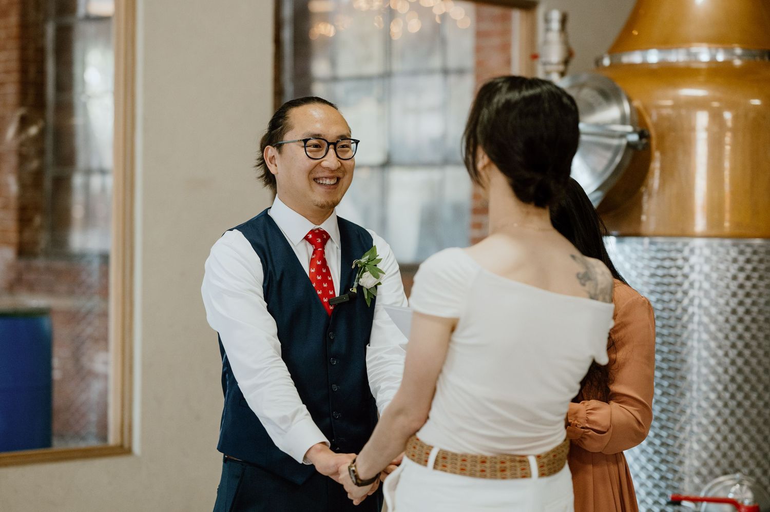 A couple during their ceremony in front of copper distilling equipment.