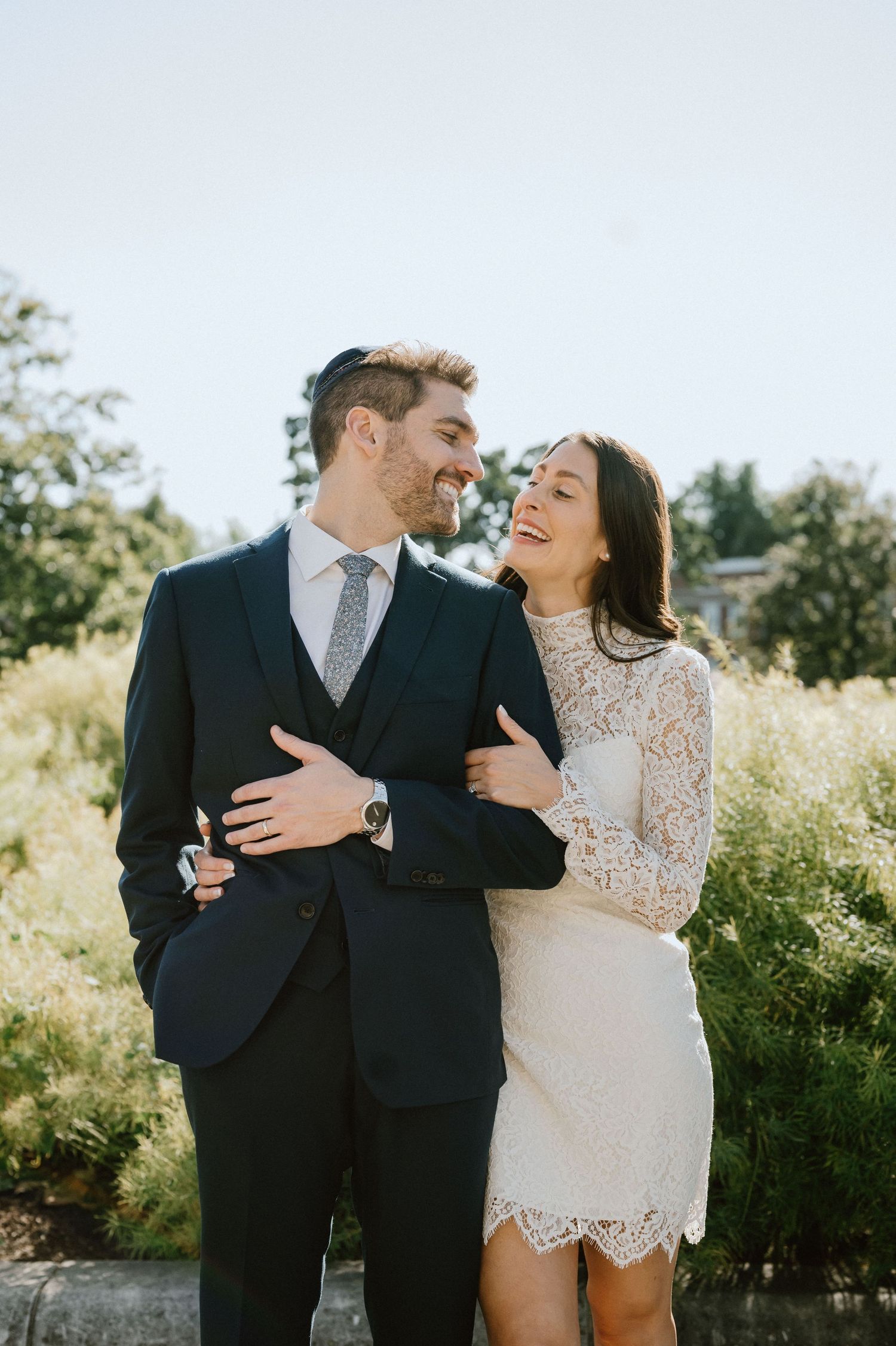 A joyful couple in formal attire sharing a candid laughing moment outdoors.