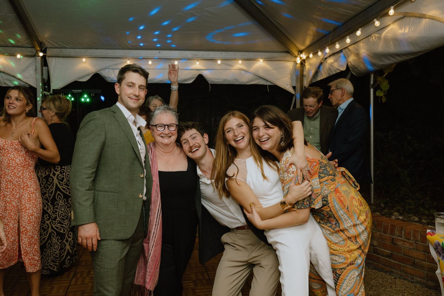 A lively celebration under a tent with party guests dancing and enjoying themselves at a festive evening event.