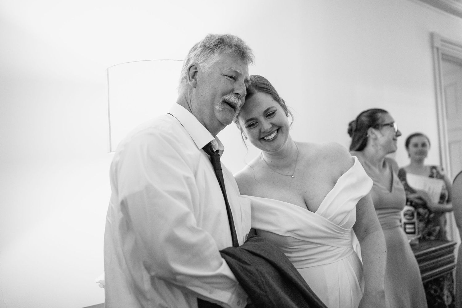 Wedding guests share laughter and embraces during an indoor celebration.