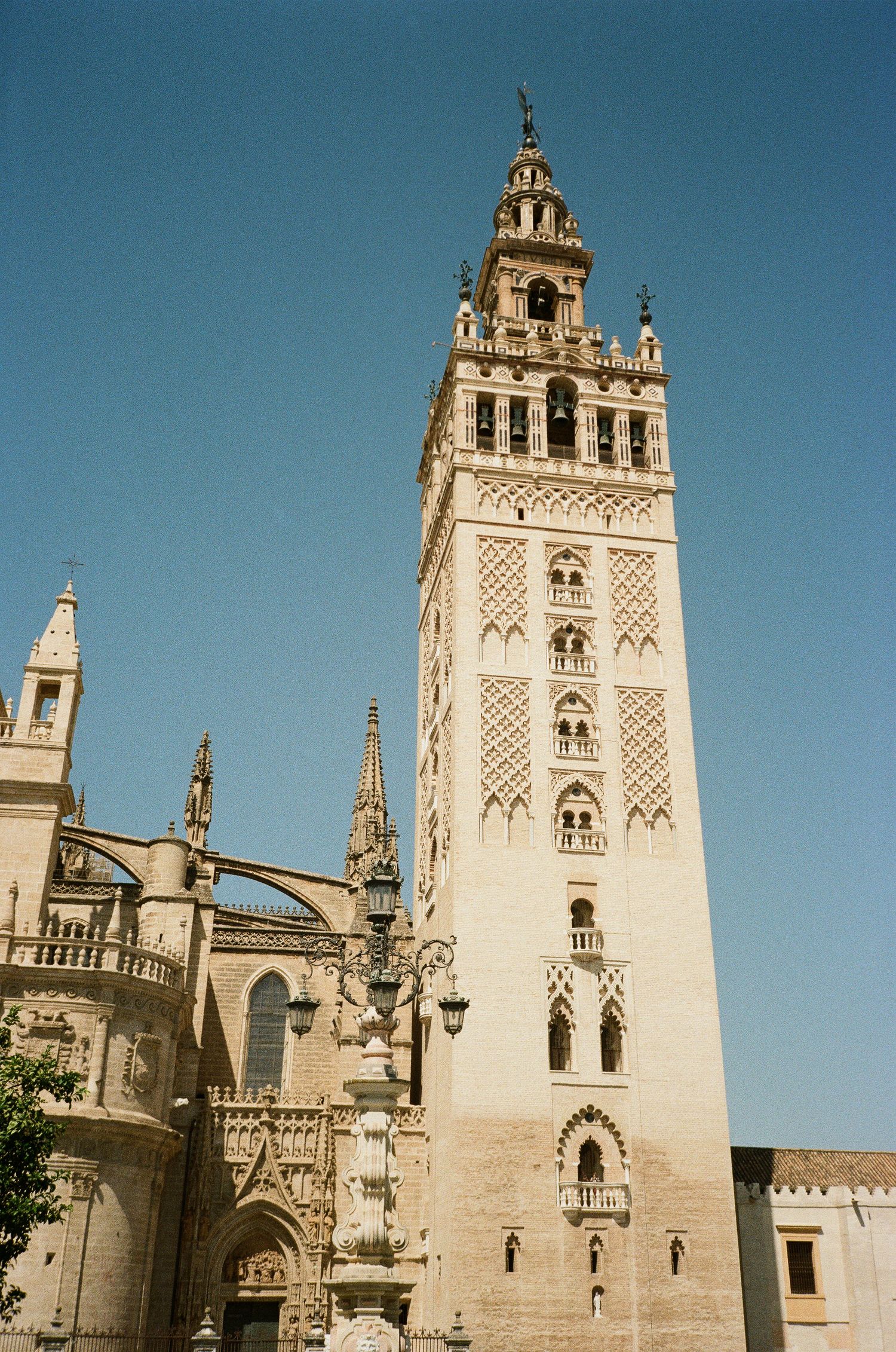 The ornate Gothic tower of Seville Cathedral rises against a clear blue sky.
