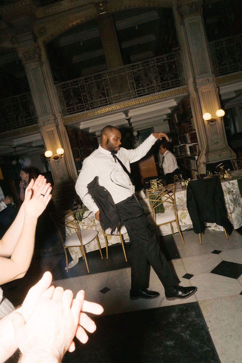Silhouettes of people dancing at an elegant indoor venue with ornate architectural details.