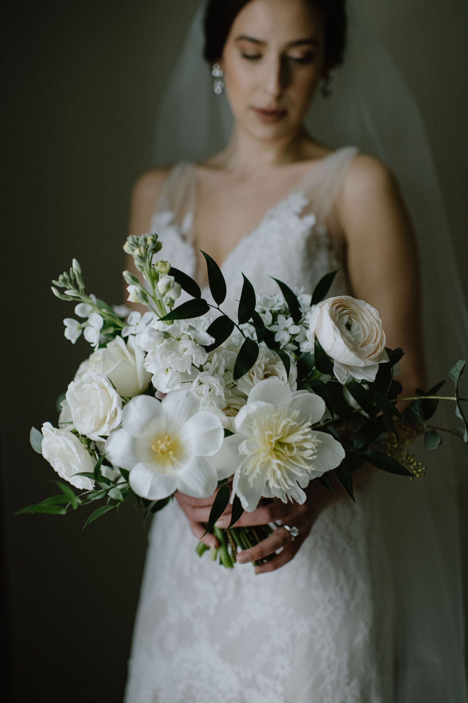 Elegant white wedding bouquet with roses, peonies and delicate greenery.