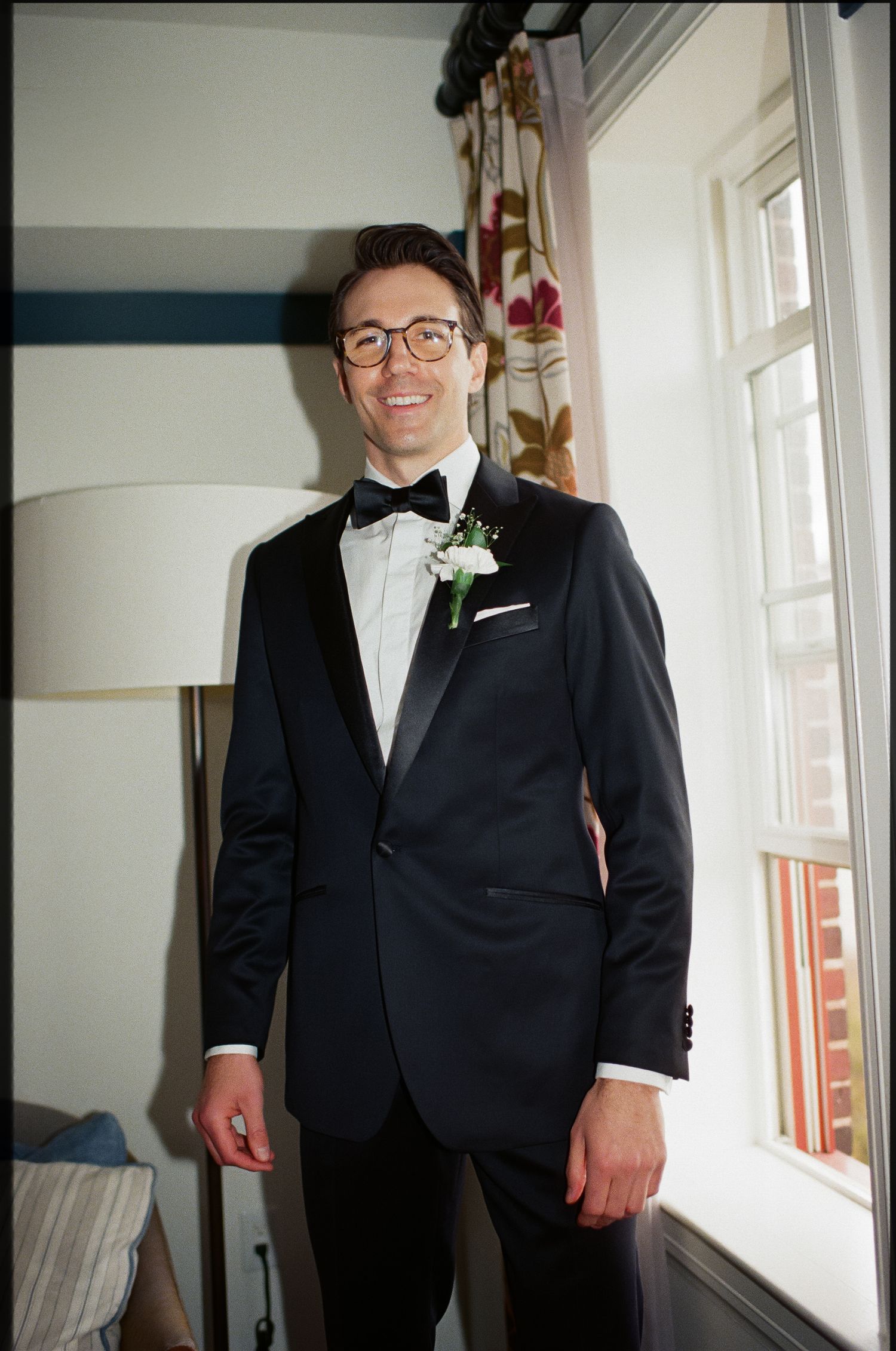 Classic formal portrait of a groom wearing black tuxedo with bowtie and boutonniere.