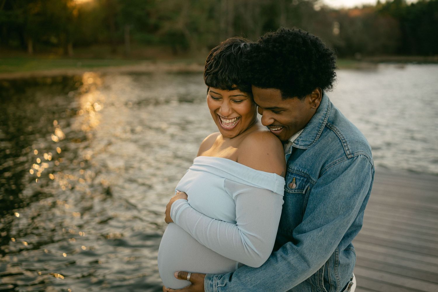 pregnant woman smiles at man with water glistening in background