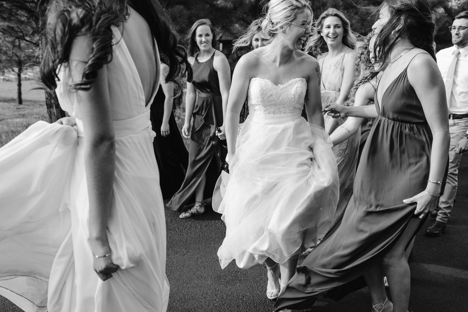 Wedding party dancing and celebrating on outdoor pavement in black and white.