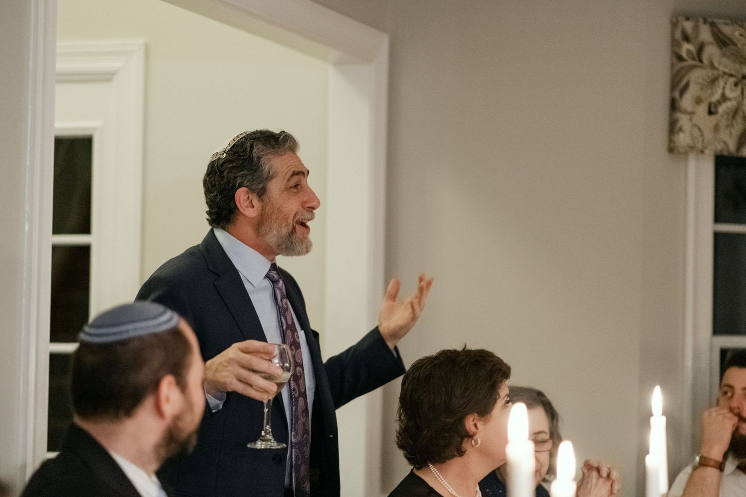 Wedding guest giving an animated toast speech at an elegant candlelit reception dinner.