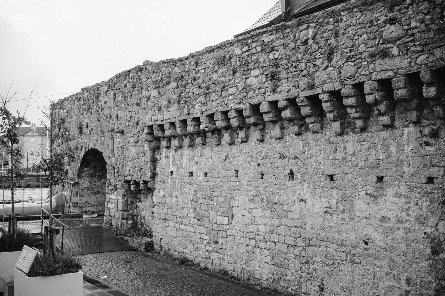 Black and white image of historic stone wall with medieval architectural details.