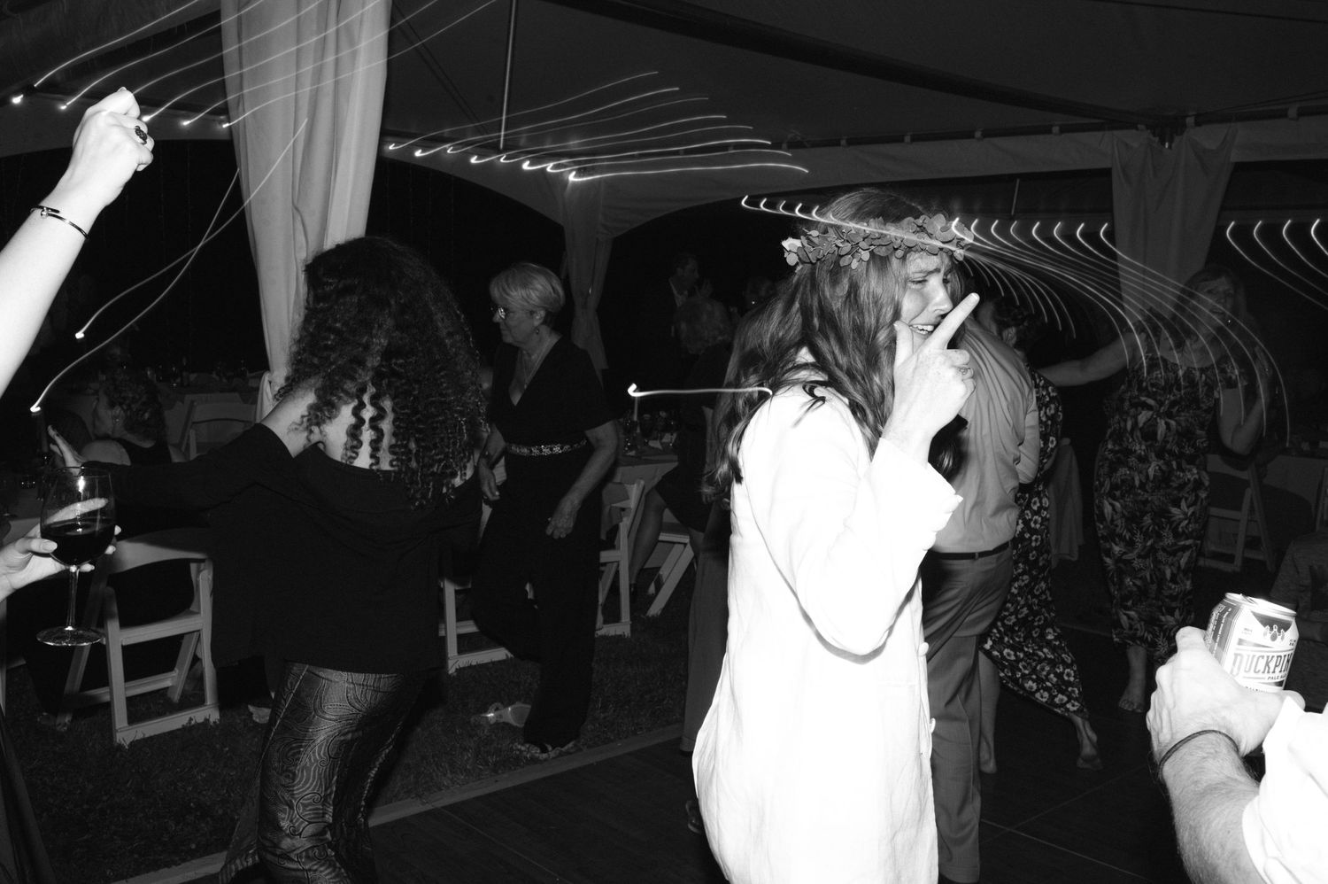 Wedding guests dancing and celebrating at a dimly lit indoor reception.
