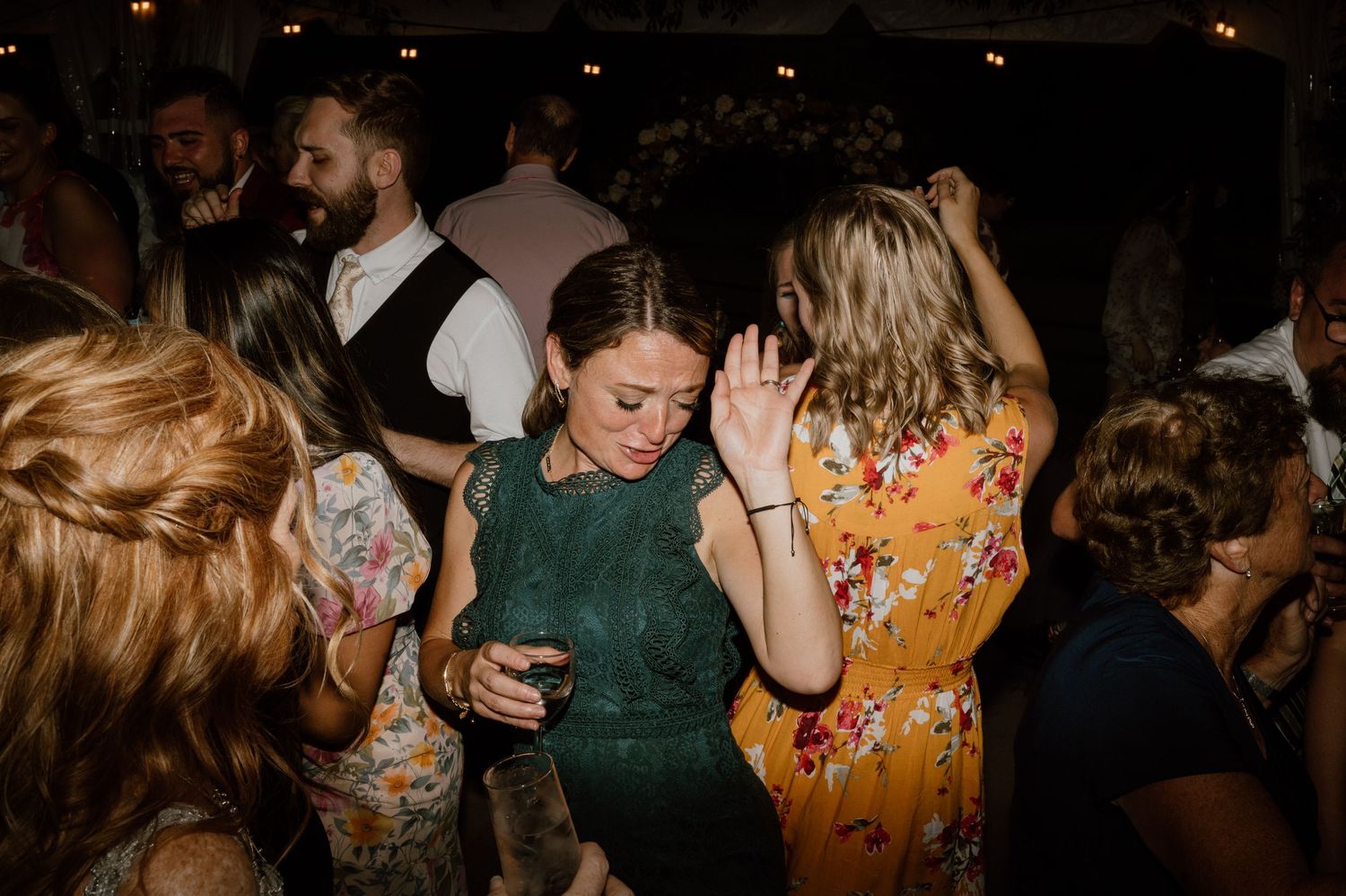 Wedding reception guests dancing and celebrating in cocktail attire at an evening event.